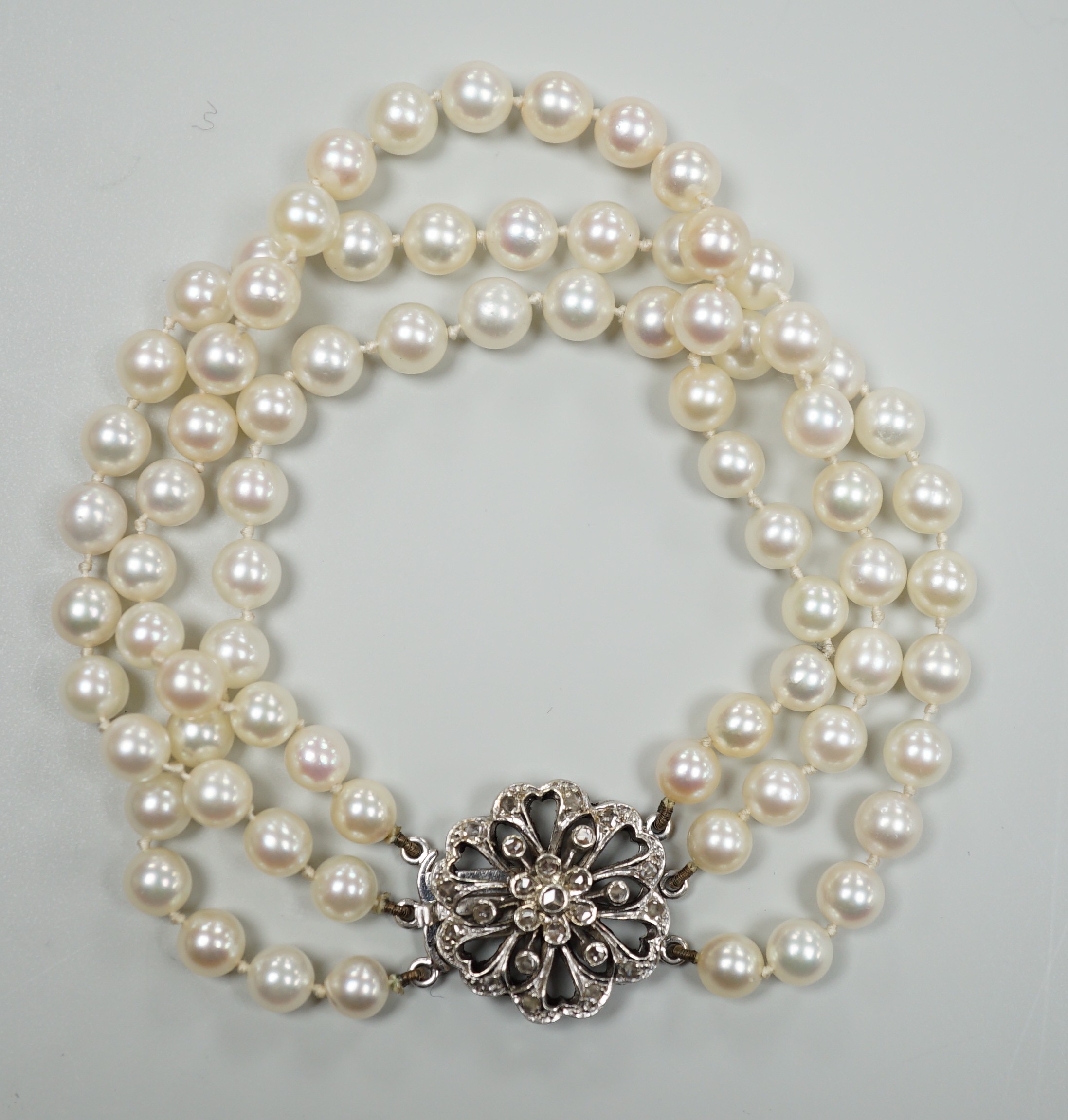 A 1960's triple strand cultured pearl bracelet, with 9ct white gold and diamond chip set clasp, 20cm.